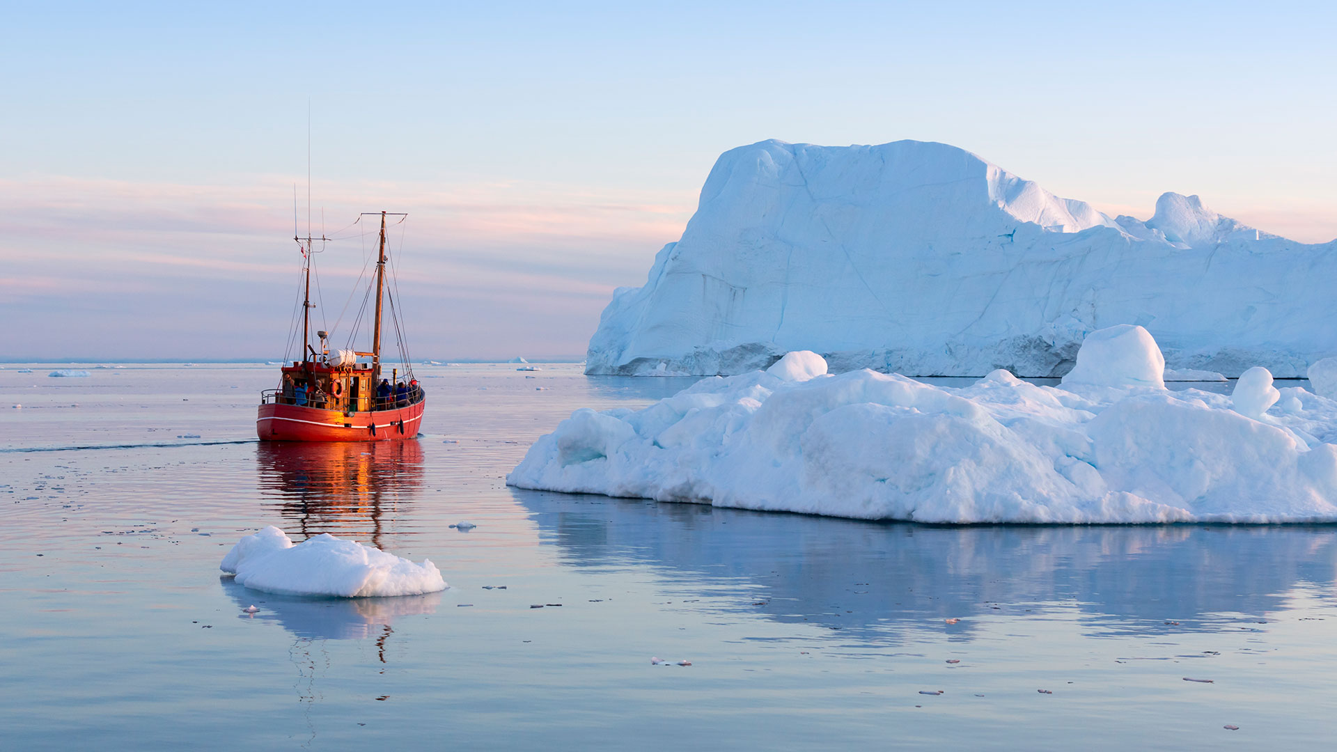 Boat sailing past icebergs in Greenland