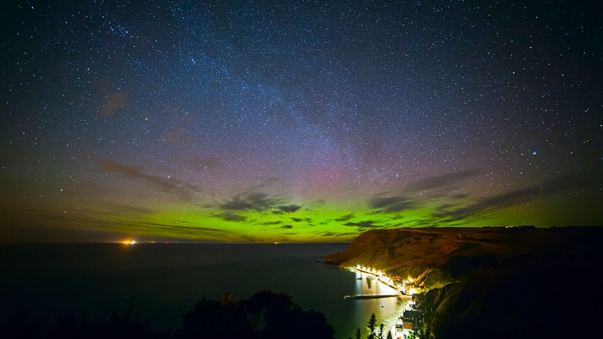 northern lights glowing green and purple above Cullen bay